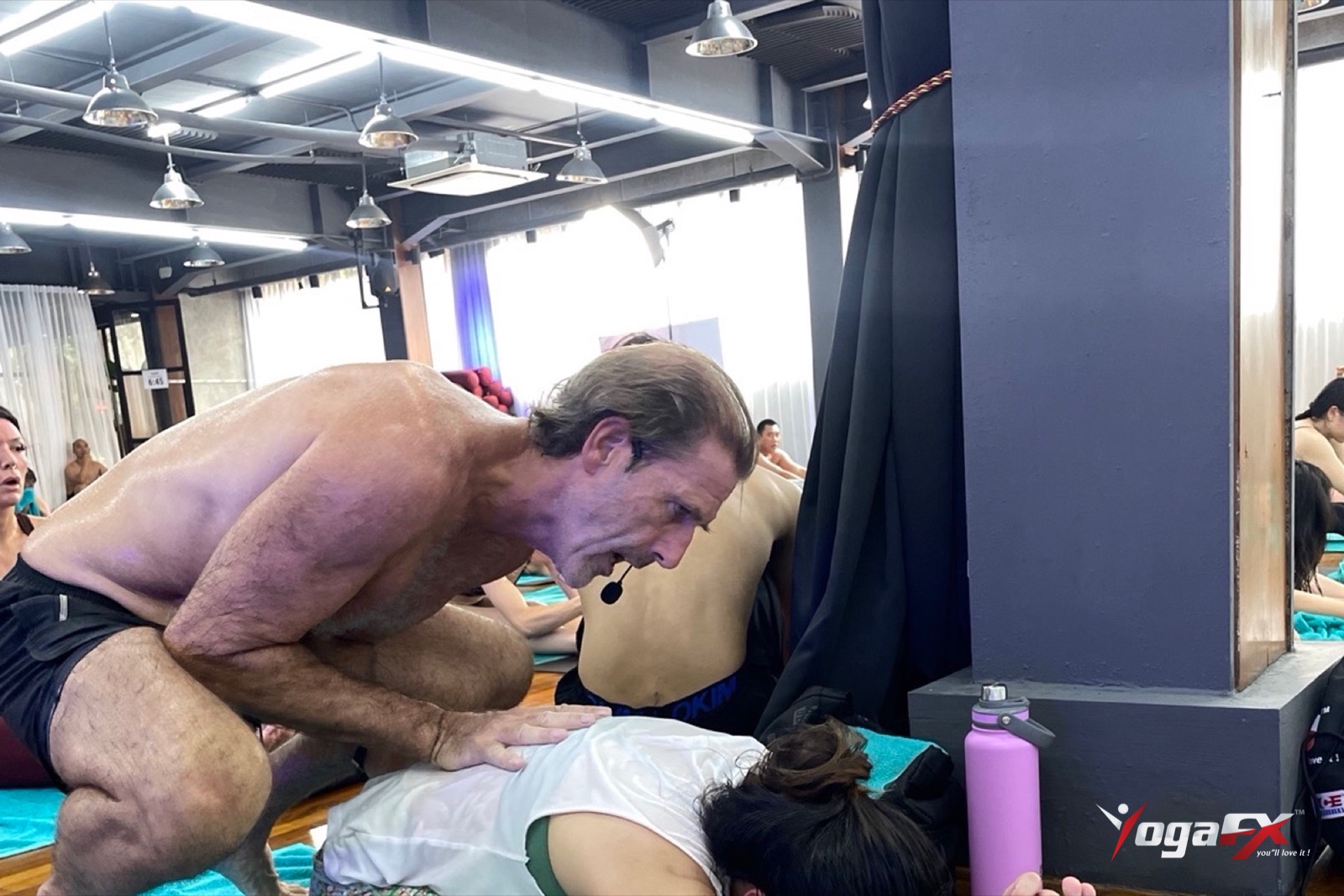 Mr. Ian Terry cueing a student up close in the heated studio, the hands-on coaching men get in a hot yoga class